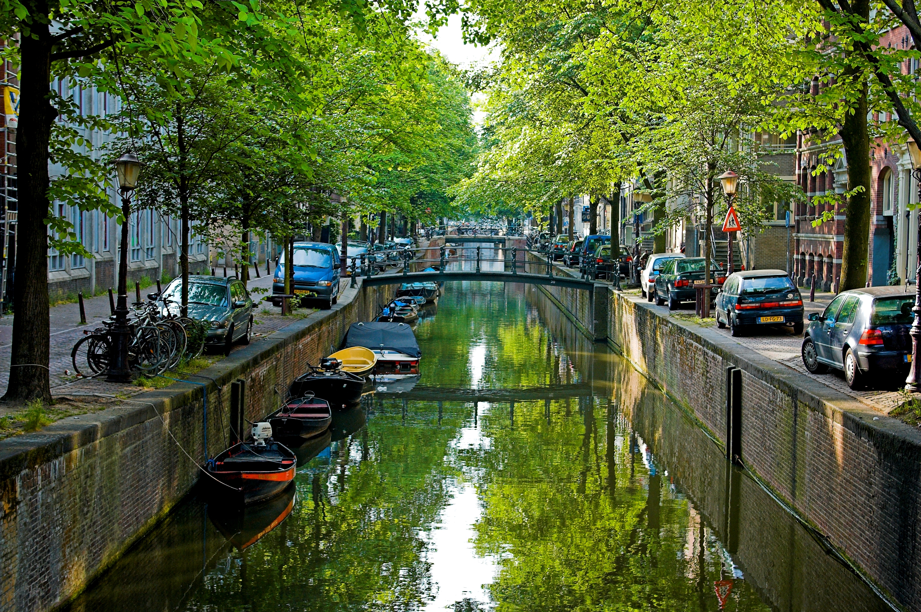 Amsterdam canal lined with houseboats and gabled houses in morning light