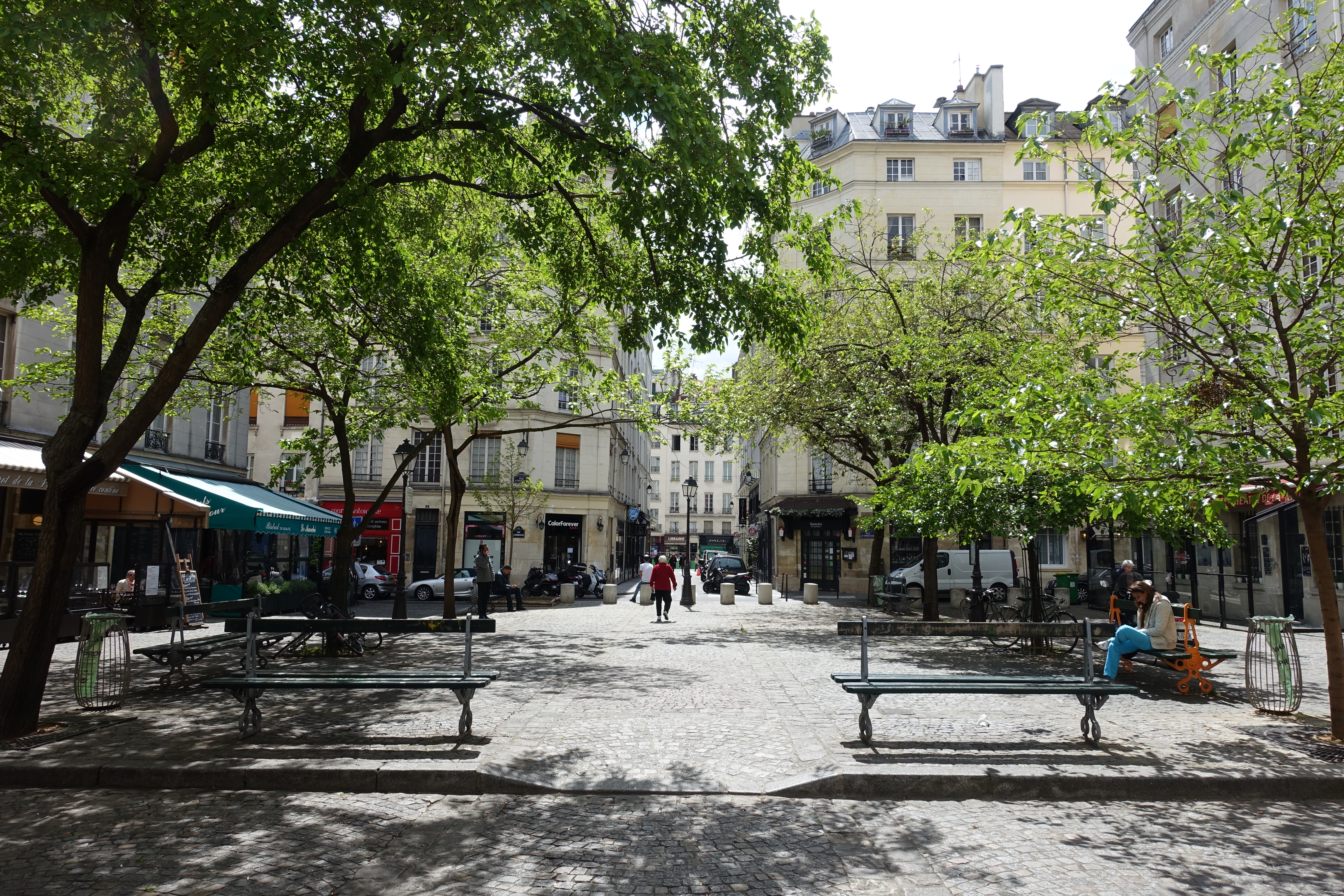 Charming Le Marais street in Paris with historic buildings and café terraces